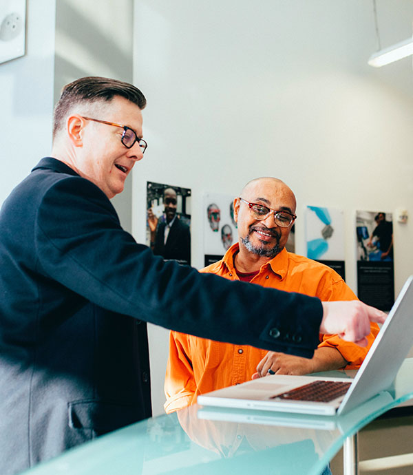 Two men talking and pointing at a laptop