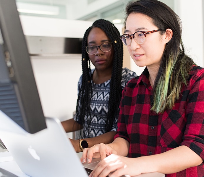 two women working at a laptop together