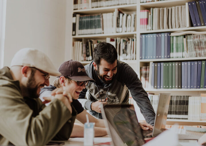 Man smiling and looking at a laptop screen with others