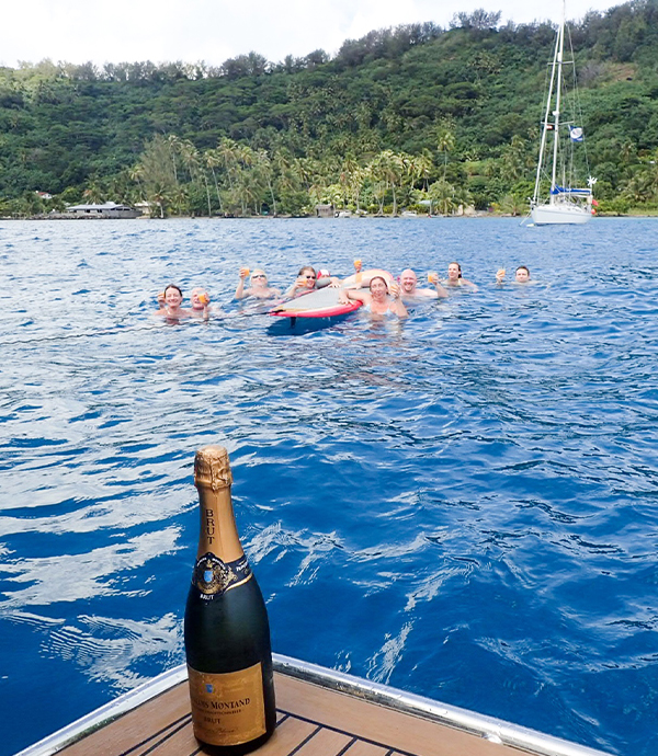 Group of people swimming in the ocean near a sail boat